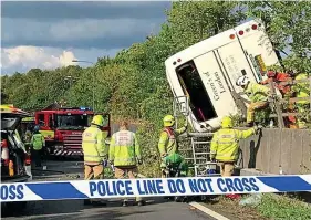  ??  ?? Cordoned off: Emergency workers examine the upturned coach
