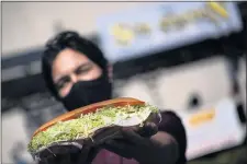  ?? CINDY YAMANAKA — STAFF PHOTOGRAPH­ER ?? The Sub Station manager Cristian Duran holds the restaurant’s signature sandwich, “Big Dude,” one year after the coronaviru­s shutdown.