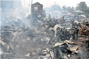  ?? KHALIL SENOSI/THE ASSOCIATED PRESS ?? The remains of market stalls smoulder after a fire swept through the marketplac­e in Nairobi, Kenya on Thursday. Fifteen people have died in the fire and about 70 were injured, some critically.