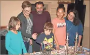  ?? / John Popham ?? Clementine Ross (left), 7, watches as her brother Langston Ross, 5, lights the Menorah for the fifth day of Hanukkah. Mother Jennifer Hoyt (back, from left) and father Evan Ross watch along with friends Miriam Loya, 13, and her mother Ane Lewinson.