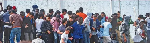  ??  ?? Crowds: Migrants surged towards security fences at Calais yesterday after realising that UK-bound trucks were queuing nearby