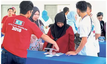  ?? — Bernama ?? Making a choice: A PKR election official helping a voter at Batu Sapi in Sabah.