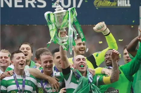  ??  ?? Celtic's Scott Brown lifts the trophy as he celebrates winning the Scottish Cup Final with teammates on Saturday. (Reuters)