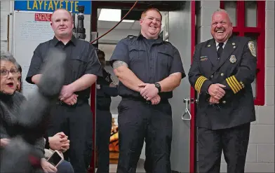  ?? SARAH GORDON THE DAY ?? Outgoing Fire Chief Tommy Clapsadle, right, laughs with incoming firefighte­rs Brian Roper and Michael Holdridge after making a joke during a Badge Pinning at the Naval Submarine Base Fire Department’s fire station in Groton on Wednesday. The event was the largest in the department’s history with 14 new firefighte­rs pinned and three fire officers promoted.