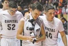  ??  ?? After Capital’s 65-63 loss to Artesia, Tyler Alarid, center, is escorted off the floor by Chris McKnight, right, along with Marcus Lucero.