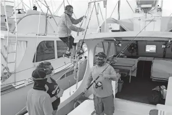  ??  ?? Captain Glenn Miller climbs to the bridge on his sport fishing boat GonFishin V; while mate Josh Rabon, right, explains to his guests what to expect during the planned day of fishing off the Florida Keys, Monday, in Islamorada, Fla. [ANDY NEWMAN/FLORIDA KEYS NEWS BUREAU VIA THE ASSOCIATED PRESS]