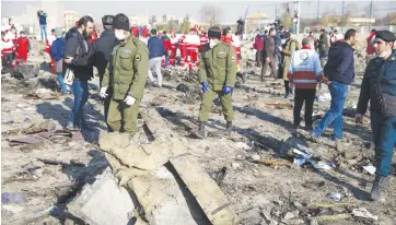  ?? (WANA/Reuters) ?? SECURITY OFFICERS and Red Crescent workers inspect the site where a Ukraine Internatio­nal Airlines plane crashed after takeoff near Tehran in January.