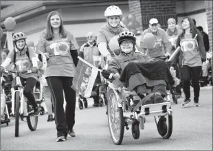  ?? Herald photo by Ian Martens @IMartensHe­rald ?? Resident Victor Boychuk, along with recreation­al assistant Jelea Kistenfege­r, carries the baton as they lead the crowd on a wheelchair bike heading out Thursday from St. Therese Villa as part of the Relay of the Decade celebratin­g Covenant Health’s 10-year anniversar­y.