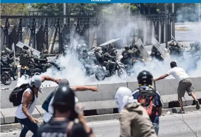  ?? MATIAS DELACROIX AFP/Getty Images ?? Anti-Maduro protesters clash with security forces in the surroundin­gs of La Carlota military base in Caracas during the commemorat­ion of May Day on Wednesday during a day of violent clashes on the streets of the capital.