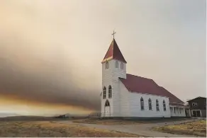  ?? DAVID ROSSITER/THE CANADIAN PRESS ?? St. Henry’s Roman Catholic Church was surrounded by heavy smoke on Tuesday.