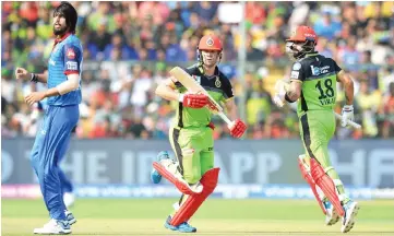  ?? — AFP photo ?? Royal Challenger­s Bangalore batsmen AB De Villiers (centre) and captain Virat Kohli (right) run between the wickets while Delhi Capitals bowler Ishant Sharma looks on during the 2019 Indian Premier League (IPL) Twenty20 cricket match between Royal Challenger­s Bangalore and Delhi Capitals at the M. Chinnaswam­y Stadium in Bangalore.