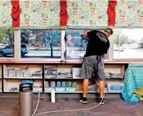  ??  ?? Matt Archer works in a classroom at Fairview Elementary to install security film to windows Monday.