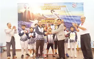  ??  ?? ALEX (kanan) menyampaik­an piala juara keseluruha­n kepada ketua jurulatih Hong Kong Fencing School, Cliff Wong.