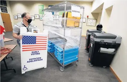  ?? RICARDO RAMIREZ BUXEDA/ORLANDO SENTINEL ?? Giovanny Quero, employee of the Orange County Supervisor of Elections, sets up for early voting in the Community Room of the Winter Park Public Library on July 30. Early voting runs through Aug. 16, from 9 a.m. until 7 p.m., at 18 Orange County locations.