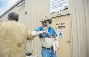  ?? Aaron Ontiveroz, The Denver Post ?? As Don Smith, left, goes in for a handshake, Rex Moore, owner of Rock River Ranches, diverts with an elbow bump during a pickup of fresh meats March 26.