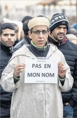  ?? Jean-Philippe Ksiazek AFP/Getty Images ?? “NOT IN MY NAME” reads a placard held by a Muslim man near the mosque in Saint-Etienne, after the January 2015 massacre at the Charlie Hebdo magazine.