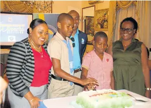  ??  ?? Deandra Whyte (left), a teacher at Broughton Primary School, watches as her student, Nathaniel Sinclair, and Tianray Barnes, student of Mount Airy Primary, cut a cake in celebratio­n of their schools’ success in two quiz competitio­ns. Dr Andrew Spencer, executive director of the Tourism Product Developmen­t Company, and Tianray’s teacher, Andrea Campbell, look on.