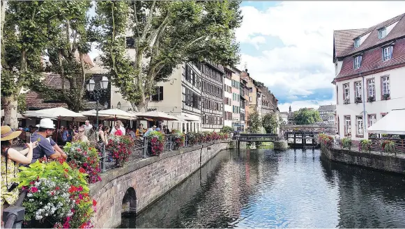  ?? RICK STEVES ?? Strasbourg’s half-timbered buildings provide a Germanic backdrop for an Alsatian meal on this riverfront terrace. The city is filled with open spaces just like this.