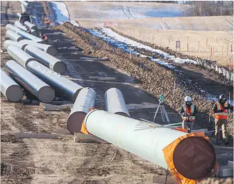  ??  ?? Workers survey around pipe to start right-of-way constructi­on for the Trans Mountain Expansion Project, in Acheson, Alta. The 22-month timeline will have the twinned facility to Burnaby nearly triple capacity to 890,000 barrels of oil per day, in service by late 2022.