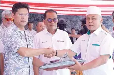  ?? ?? Mohamed Khaled (centre) witnessing the handing over of a replica of the FIC G2000 Mk II from Hj Jamalolail (right) to Abdul Rahman.