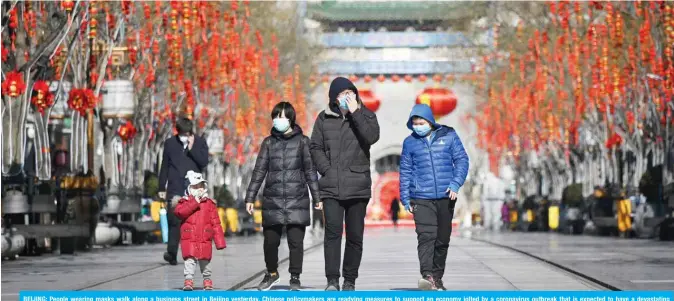  ?? AFP ?? BEIJING: People wearing masks walk along a business street in Beijing yesterday. Chinese policymake­rs are readying measures to support an economy jolted by a coronaviru­s outbreak that is expected to have a devastatin­g impact on first-quarter growth, policy sources said.—