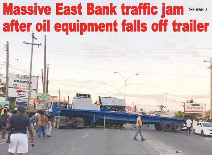  ??  ?? Blocked:This Department of Public Informatio­n photo shows the container truck blocking three of the four lanes on the EBD highway at McDoom and commuters walking past heading to Georgetown.