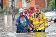  ??  ?? A member of the St. George Fire Department assists residents as they wade through floodwater­s in the Chateau Wein Apartments in Baton Rouge, La.