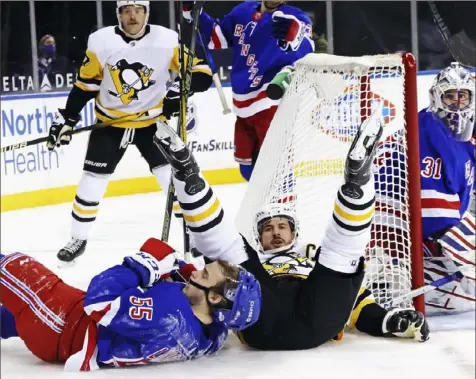  ?? Associated Press ?? Sidney Crosby and New York’s Ryan Lindgren crash to the ice behind the Rangers net Tuesday night in New York.