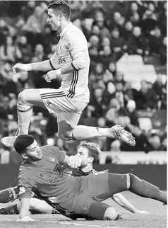  ??  ?? Cristiano Ronaldo (top) jumps over Real Sociedad’s Argentinia­n goalkeeper Geronimo Rulli during the Spanish league football match Real Madrid CF vs Real Sociedad at the Santiago Bernabeu stadium in Madrid. — AFP photo