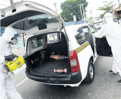  ?? RUDOLPH BROWN/PHOTOGRAPH­ER ?? Jovan Robinson (left) and Ranniese Adam, of Mint Cleaners Ltd, sanitising taxis in Half-Way Tree, St Andrew, on Sunday. The bill was underwritt­en by the Ministry of Transport and Mining.