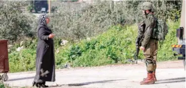  ?? Agence France-presse ?? ↑ A Palestinia­n woman speaks with an Israeli soldier at a checkpoint near Nablus in occupied West Bank on Sunday.