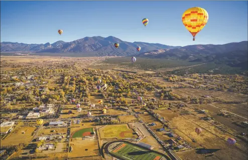  ?? NATHAN BURTON/Taos News ?? Dozens of hot air balloons rise over Taos during the 38th annual Taos Mountain Balloon Rally on Saturday (Oct. 30).