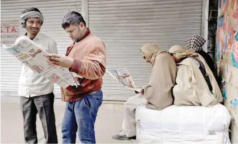  ?? — Reuters ?? Men read newspapers in a market area on a cold winter morning in the old quarters of Delhi on Tuesday.