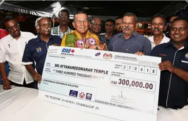  ??  ?? Community gesture: Mohd Shafei (yellow batik) presenting a mock cheque to Sri Ayyanarees­warar Temple assistant secretary Raj Kumar R. Narayanan at the Nadi Raykat’s service centre in Taman Danau Kota, Kuala Lumpur.