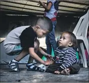  ?? Gina Ferazzi Los Angeles Times ?? A HONDURAN boy plays with a Salvadoran toddler at a Tijuana border shelter. Their families are fleeing violence at home and seeking asylum in the U.S.