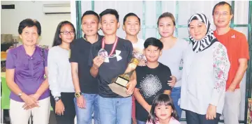  ??  ?? Harith (fourth left) holds the Ong Beng Hee Cup and KL Junior Open medal as he poses with his family. His parents Jefri Ahmad and Nur Farhana are at far right.