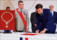 ?? (Photo AFP) ?? ▲ Emmanuel Macron signant le protocole sous les yeux du grand chancelier de la Légion d’honneur Benoît Puga et de Jean Castex.