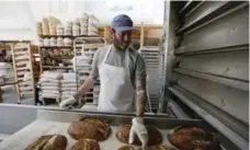  ??  ?? Chad Robertson looks over loaves of bread coming out of an oven at the Tartine Manufactor­y.