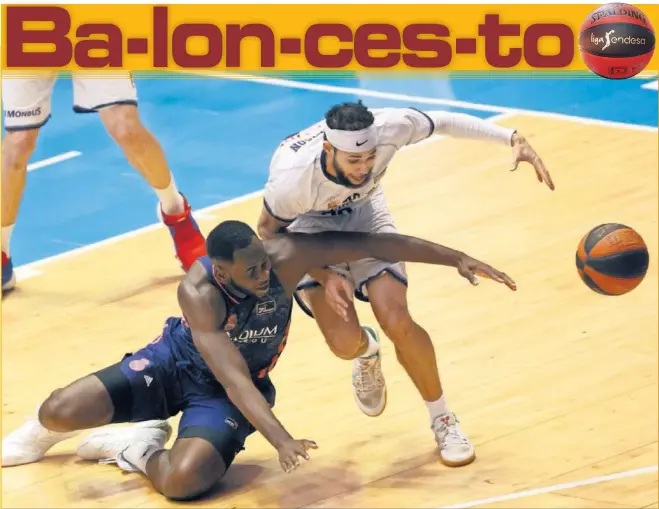  ??  ?? Usman Garuba, pívot del Real Madrid, se lanza al suelo para intentar quitarle el balón a Kassius Robertson, escolta del Monbus Obradoiro. Los dos jugaron un buen partido.