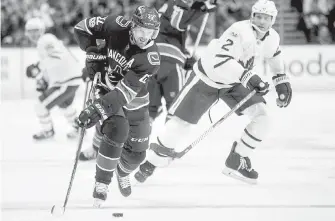  ?? THE CANADIAN PRESS ?? The Canucks’ Daniel Sedin skates away with the puck while being watched by Toronto Maple Leafs’ Ron Hainsey during the first period in Vancouver on Saturday.