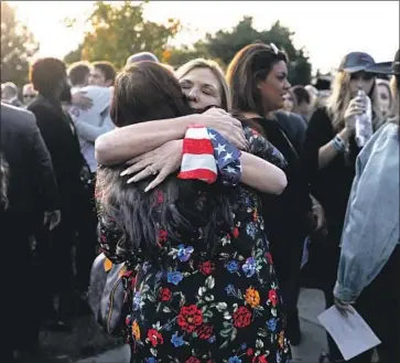  ?? Photograph­s by Francine Orr Los Angeles Times ?? HOLDING a U.S. flag in her hands, Laura Lynn Meek hugs a woman at a service Saturday for her slain son.
