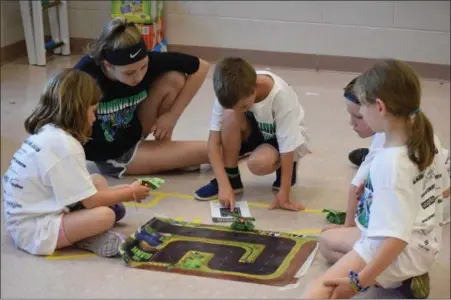  ?? Marian DenniS — MeDianeWS groUP ?? campers at camp invention program their orbots to follow a map laid out on the floor. the campers had been working all week learning about science and technology related to their projects.