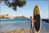  ?? Associated Press ?? Bryant de Venecia with his paddleboar­d in Honolulu on Nov. 11. He is among the Hawaii residents feeling ambivalenc­e toward tourists returning now that the state is allowing incoming travelers to bypass a 14-day quarantine with a negative COVID-19 test.