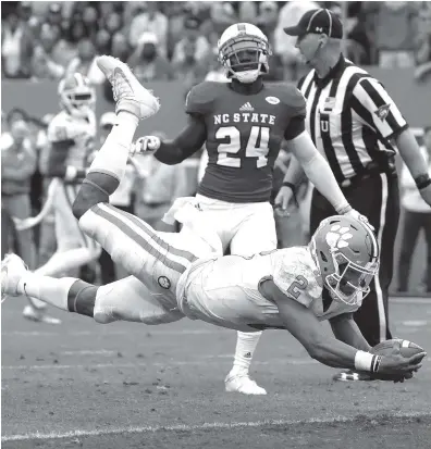  ?? THE ASSOCIATED PRESS ?? Clemson quarterbac­k Kelly Bryant dives into the end zone for a touchdown while North Carolina State’s Shawn Boone looks on during the first half Saturday in Raleigh, N.C.
