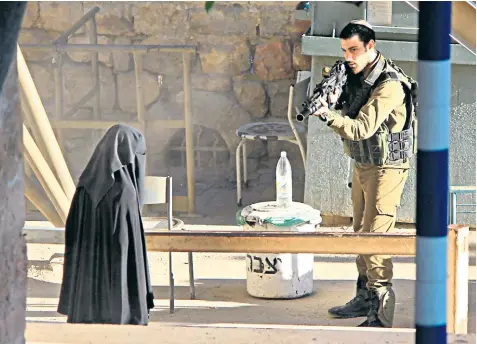  ??  ?? Hadeel al-Hashlamun at the checkpoint with an Israeli soldier brandishin­g a rifle at her, in a photograph from a series published online by the Youth Against Settlement­s group