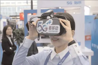  ?? -AFP ?? A visitor tries a 5G-enabled device of China Mobile during an industry expo in Chinese Jiangsu province.