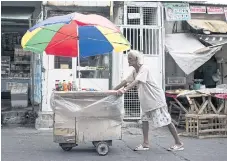  ??  ?? DAILY GRIND: Al Enriquez, 82, also known as Carmen Dela Rue, pushes his wooden cart on a street in Manila.