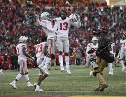  ?? NICK WASS — THE ASSOCIATED PRESS ?? Ohio State cornerback­s Tyreke Johnson (13) and Kendall Sheffield, left center, celebrate after a 52-51 overtime win at Maryland on Nov. 17.