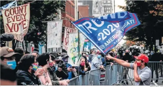  ?? MÁRIO CRUZ / EFE ?? Un seguidor de Trump agita una bandera hacia los seguidores de Biden en las afueras de un centro de recuento de votos, el jueves en Filadelfia.