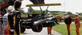  ??  ?? Picking up the pieces: Renault’s British driver Jolyon Palmer (second from left) looks on as his racing car is lifted off the racetrack after a tyre blow-out during a practice session at the Hungarorin­g racing circuit in Budapest yesterday. – AFP